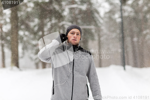 Image of sports man with earphones in winter forest