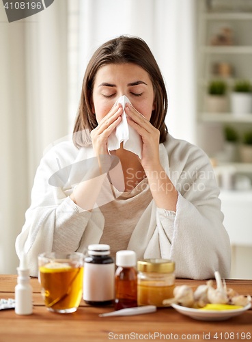 Image of sick woman with medicine blowing nose to wipe