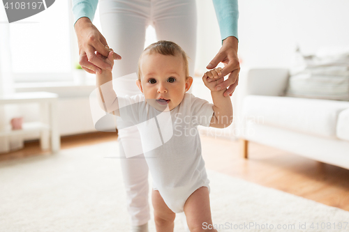 Image of happy baby learning to walk with mother help