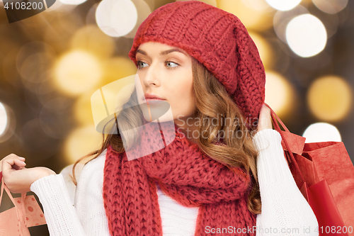 Image of woman in red hat and scarf holding shopping bags