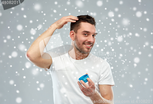 Image of happy young man styling his hair with wax or gel