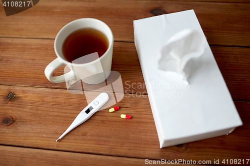 Image of cup of tea, paper wipes and thermometer with pills