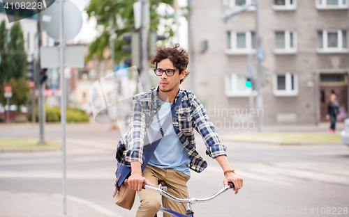 Image of young hipster man with bag riding fixed gear bike