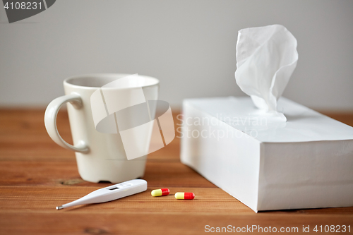 Image of cup of tea, paper wipes and thermometer with pills