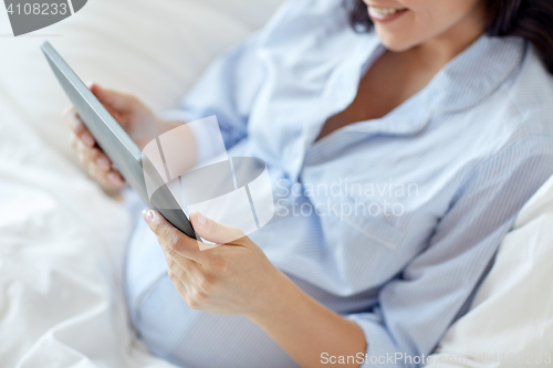 Image of close up of pregnant woman with tablet pc at home