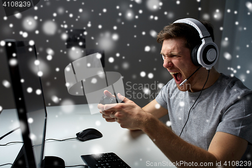 Image of man in headset playing computer video game at home