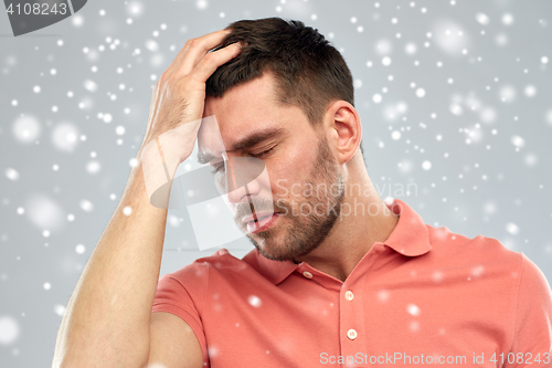 Image of unhappy man suffering from head ache over snow