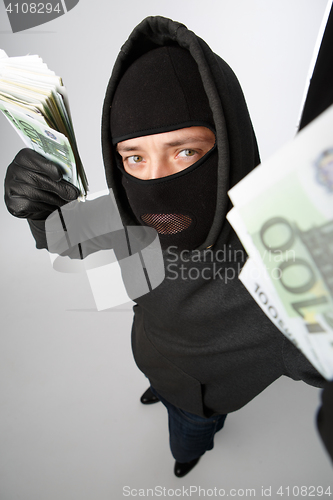 Image of Burglar in black mask holds banknotes