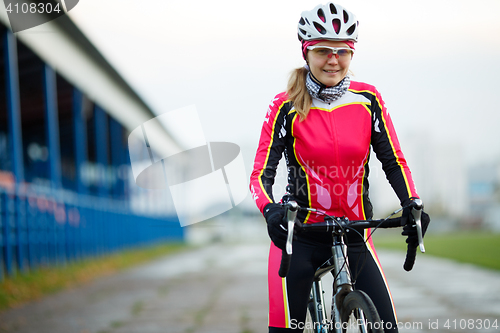 Image of Slender athletic female cyclist in black-and-red track suit