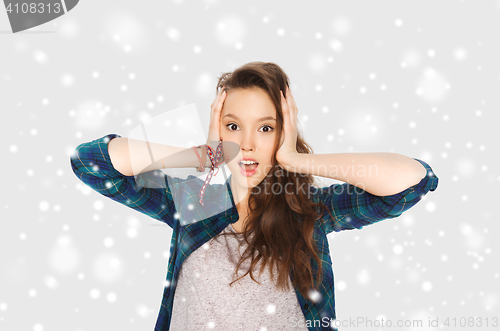 Image of teenage girl holding to head over snow