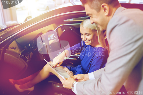 Image of happy woman with car dealer in auto show or salon