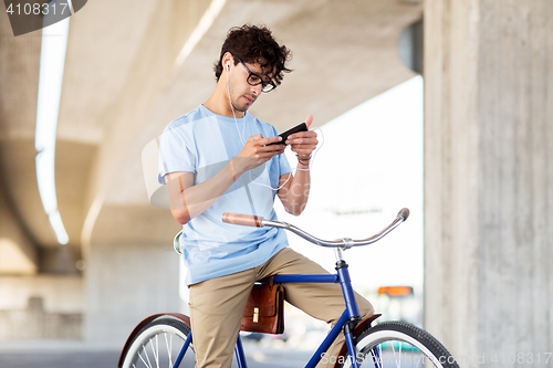 Image of man with smartphone and earphones on bicycle