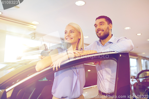 Image of happy couple buying car in auto show or salon