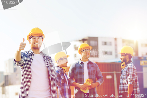 Image of group of smiling builders in hardhats outdoors