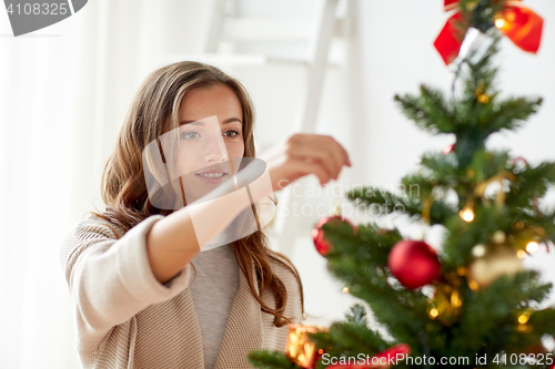 Image of happy young woman decorating christmas tree