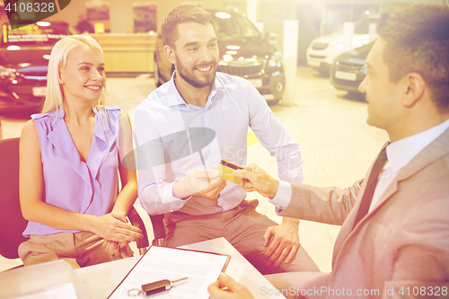 Image of happy couple with car dealer in auto show or salon