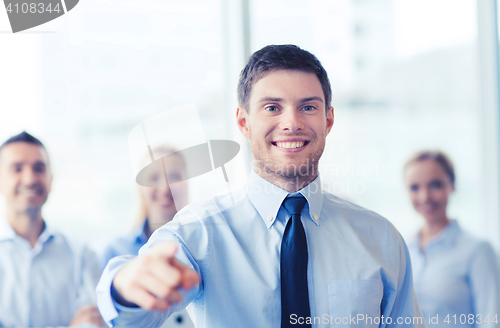 Image of smiling businessman with colleagues in office