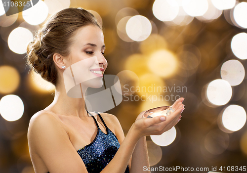 Image of smiling woman in evening dress holding diamond