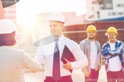 Image of group of smiling builders in hardhats outdoors