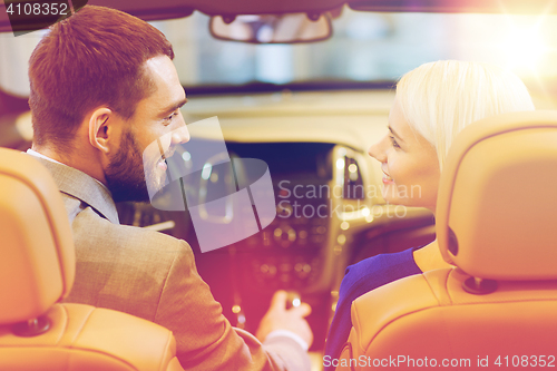 Image of happy couple sitting in car at auto show or salon