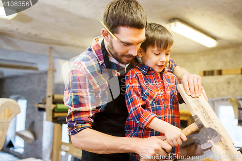 Image of father and son with ax and wood plank at workshop