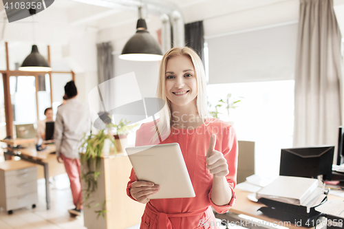 Image of woman with tablet pc showing thumbs up at office