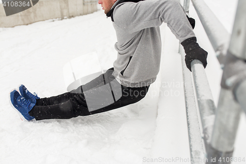 Image of sports man doing triceps dips at fence in winter