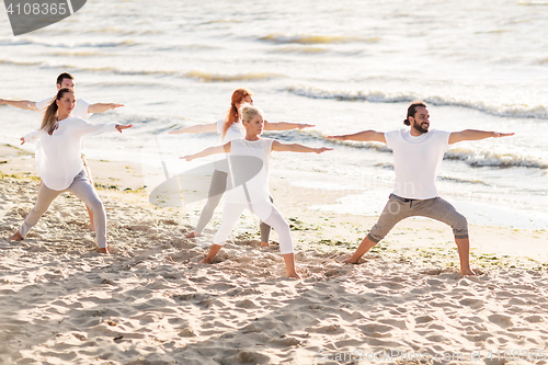 Image of people making yoga in warrior pose on beach