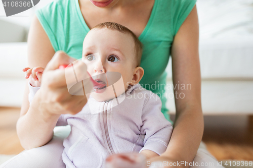 Image of mother with spoon feeding little baby at home