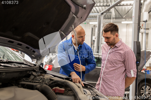 Image of auto mechanic with clipboard and man at car shop