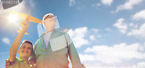 Image of senior man and boy with toy airplane over sky