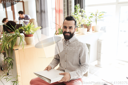 Image of happy creative male office worker with folfer