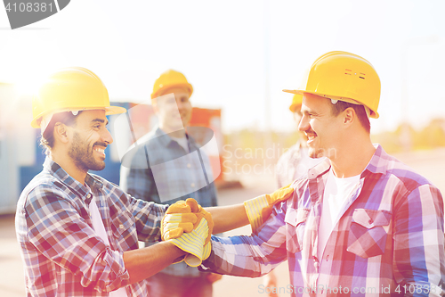 Image of group of smiling builders in hardhats outdoors