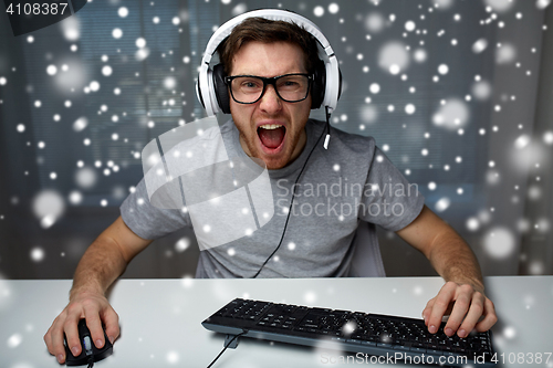 Image of man in headset playing computer video game at home