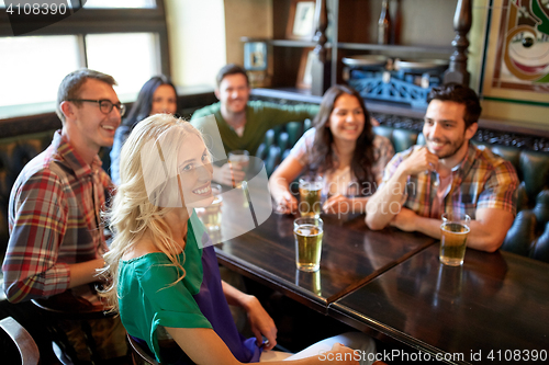 Image of friends with beer watching football at bar or pub