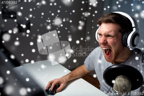 Image of man in headset playing computer video game at home