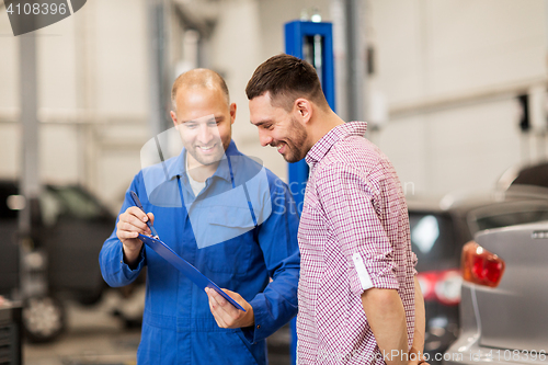 Image of auto mechanic with clipboard and man at car shop