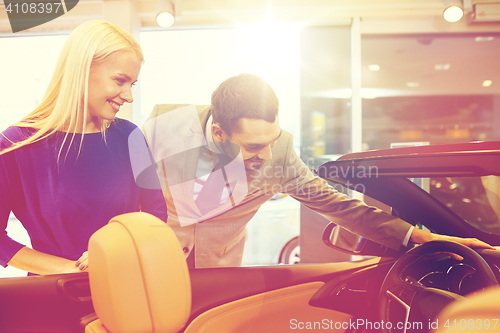 Image of happy couple buying car in auto show or salon