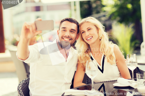 Image of happy couple taking selfie with smatphone at cafe