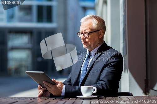 Image of senior businessman with tablet pc drinking coffee