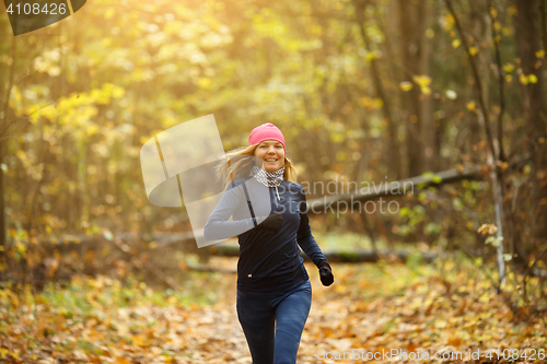 Image of Blonde woman jogging in morning in autumn park