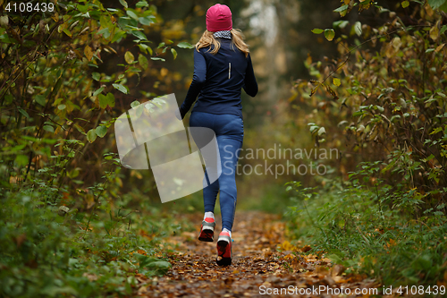Image of Young woman runs among trees