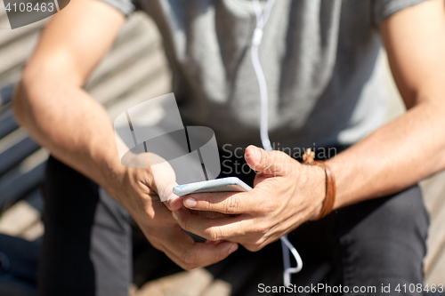 Image of close up of man with smartphone and earphones wire