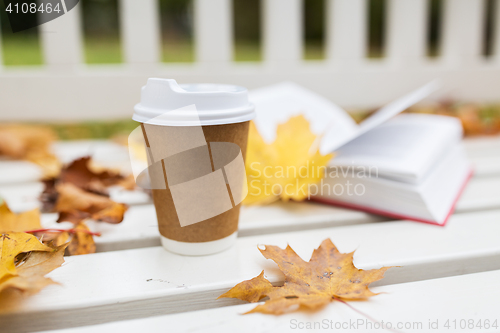 Image of coffee drink in paper cup on bench at autumn park