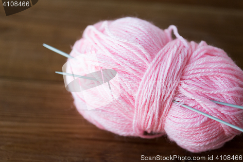 Image of knitting needles and ball of pink yarn on wood