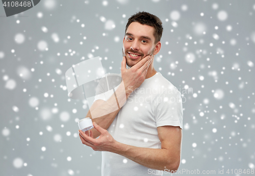 Image of happy young man with cream jar over snow