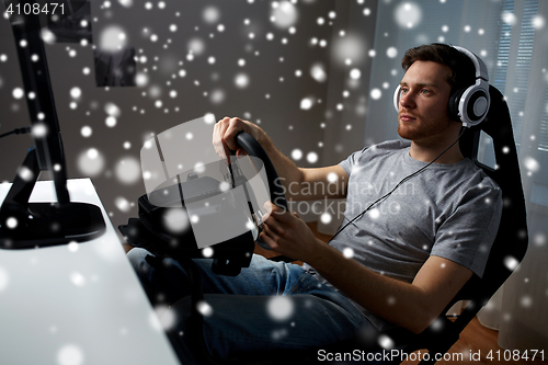 Image of man playing car racing video game at home