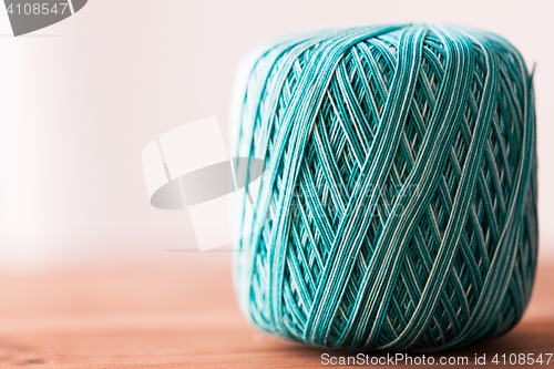 Image of ball of turquoise cotton yarn on wood