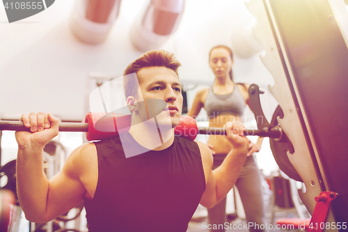 Image of man and woman with barbell flexing muscles in gym