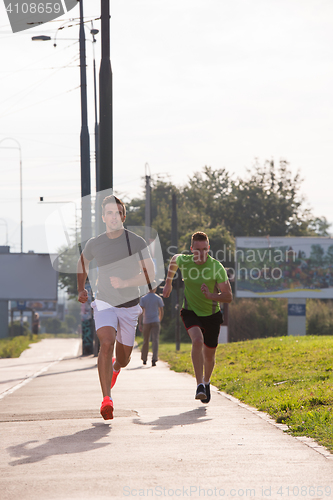 Image of Two young men jogging through the city